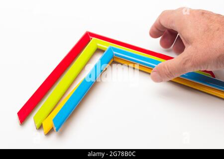 Hand, Finger und verschiedene Farben; Buntstifte, voller Bereich; farbige Winkel, die von der Hand eines Erwachsenen gehalten werden Stockfoto