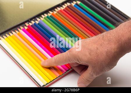 Hand, Finger und verschiedene Farben; Buntstifte, voller Bereich; farbige Winkel, die von der Hand eines Erwachsenen gehalten werden Stockfoto