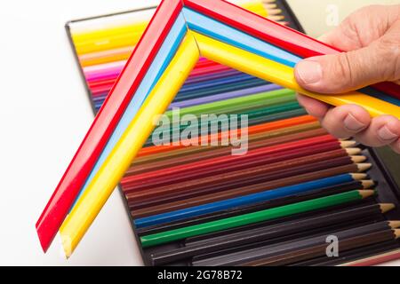 Hand, Finger und verschiedene Farben; Buntstifte, voller Bereich; farbige Winkel, die von der Hand eines Erwachsenen gehalten werden Stockfoto