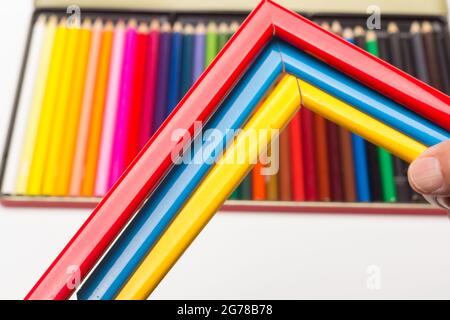 Hand, Finger und verschiedene Farben; Buntstifte, voller Bereich; farbige Winkel, die von der Hand eines Erwachsenen gehalten werden Stockfoto