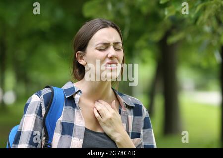 Gestresster Student mit Rachenschmerzen beim Gehen auf dem Campus oder im Park Stockfoto