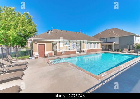 Öffentlicher Swimmingpool mit Bürogebäude und entspannenden Liegestühlen im Freien Stockfoto