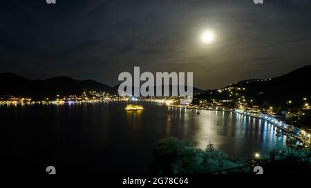 Ionische Inseln, Ithaca, Insel Odysseus, Hauptstadt, Vathi, Nachtaufnahme, Vollmond, Blick auf die Bucht, die Insel Lazareto und den beleuchteten Vathi, nächtlicher blauer Himmel mit Wolken, Mondlicht auf dem Meer Stockfoto