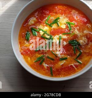 Draufsicht rote Tomate mit Eiersuppenschüssel, einfaches, billiges und schnelles Essen zum Mittagessen, aber lecker und nahrhaft Stockfoto