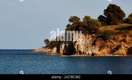 Ionische Inseln, Ithaca, Insel Odysseus, Nordostküste, Bucht von Marmakas, Überwuchert felsige Küste, blaues Meer, hellblauer Himmel Stockfoto