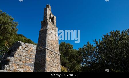 Ionische Inseln, Ithaka, Insel Odysseus, Vathi, Bezirk Perachori, Liegt auf einem bewaldeten Berghang, Kirche, Backstein Glockenturm hoch und eng, Weitwinkel-Ansicht, Himmel hellblau Stockfoto