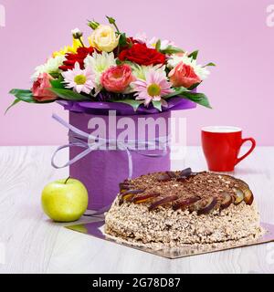 Blumenstrauß, Tasse Kaffee und Schokoladenkuchen auf Holzbrettern. Stockfoto