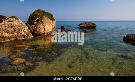 Ionische Inseln, Zakynthos, südlich der Stadt Zakynthos, Banana Beach, kleine Felsen vor dem Meer, bewachsen, meergrün und kristallklar, kleine Felsen sichtbar unter Wasser Stockfoto