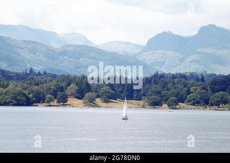 Friedliche Mäanderung. Einzelyacht auf Windermere mit den Langdale Pikes Beyond. Stockfoto