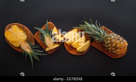 In Scheiben geschnittene Ananas in verschiedenen Formen. Reife Ananas auf Schneidebrett Kochen Sommer Dessert auf schwarzem Hintergrund. Flach liegend. Langes Webbanner Stockfoto