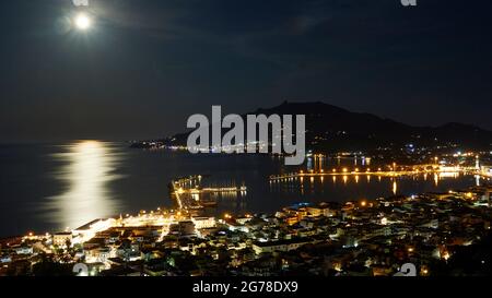 Zakynthos, Stadt Zakynthos, Stadtpanorama vom Burghügel, Hügel des Monte Yves im Hintergrund, Nachtaufnahme, Vollmond in der oberen linken Bildecke, Mondspiegelungen auf dem Wasser, beleuchtete Stadt, beleuchteter Hafen Stockfoto