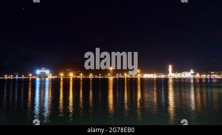 Zakynthos, Stadt Zakynthos, Nachtaufnahme, Abendaufnahme, Hafen, Blick über das Meer zum Hafen und zur nächtlichen Skyline von Zakynthos, beleuchtete Fähre, beleuchtete Kirche Agios Dionisios, Lichtreflexe auf dem dunklen Wasser Stockfoto