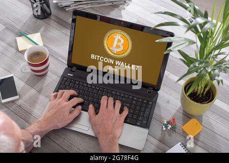 Mann, der einen Laptop mit Bitcoin-Geldbörse-Konzept auf dem Bildschirm verwendet Stockfoto