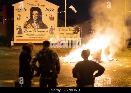 Belfast, Großbritannien. Juli 2021. In der Mitte der Straße entzündete sich ein Feuer vor einem Wandbild, das Wilhelm von Oranien in South Belfast zeigt.am 11. Juli oder in der elften Nacht wird um Mitternacht um den 12. Juli herum ein Lagerfeuer angezündet. In diesem Jahr jährt sich die Gründung Nordirlands zum hundertsten Mal und ist gleichzeitig der erste zugelassene Orangen-Marsch seit Beginn der Pandemie. Kredit: SOPA Images Limited/Alamy Live Nachrichten Stockfoto