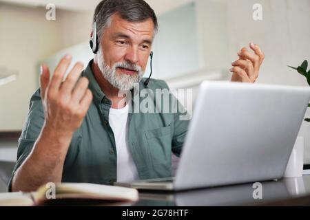 Attraktive reife männliche Fernarbeit von zu Hause und mit Arbeit confrence Videoanruf Stockfoto