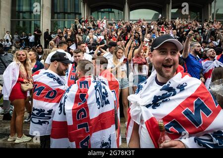 Fußballfans, die mit St Georges Flaggen drapiert sind, kommen in die Stadt, um sich das Finale der Euro 2020 anzusehen, bei dem England Italien spielt. Stockfoto