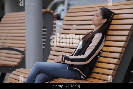 Hübsches asiatisches Mädchen sitzt auf einer Bank und entspannt - Menschen Fotografie Stockfoto