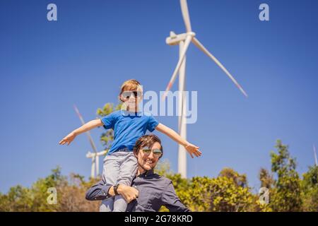 Alternative Energie, Windpark und glückliche Zeit mit der Familie. Glücklicher Vater trägt seinen Sohn auf Schultern ist im Urlaub und Flucht in die Natur. Vater Stockfoto