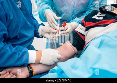 Ein nicht anerkannter Arzt, der Latexhandschuhe trägt, entzieht einem Patienten in der medizinischen Klinik Blut. Stockfoto