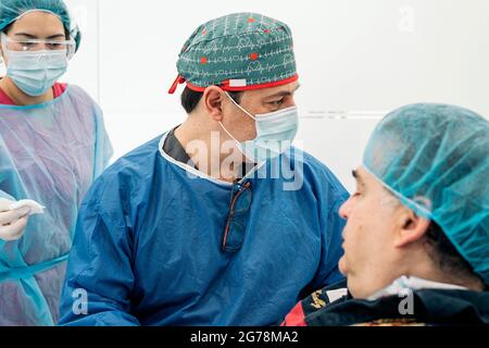 Arzt trägt Gesichtsmaske und Schutzausrüstung, die in der medizinischen Klinik mit älteren Patienten arbeitet. Stockfoto