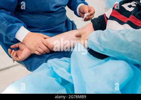 Ein nicht anerkannter Arzt entnimmt einem Patienten in der medizinischen Klinik Blut. Stockfoto