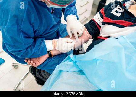 Ein nicht anerkannter Arzt entnimmt einem Patienten in der medizinischen Klinik Blut. Stockfoto