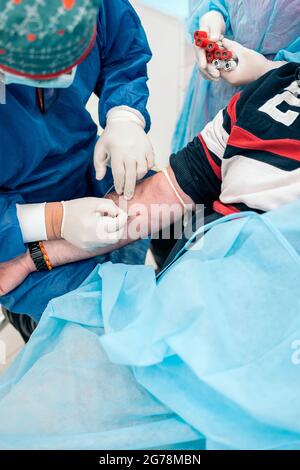 Ein nicht anerkannter Arzt entnimmt einem Patienten in der medizinischen Klinik Blut. Stockfoto