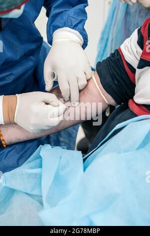 Ein nicht anerkannter Arzt entnimmt einem Patienten in der medizinischen Klinik Blut. Stockfoto
