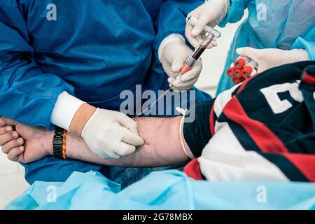 Ein nicht anerkannter Arzt, der Latexhandschuhe trägt, entzieht einem Patienten in der medizinischen Klinik Blut. Stockfoto