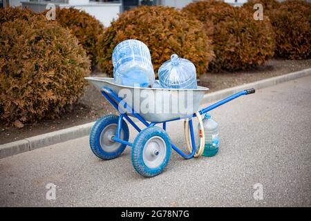 Gartenwagen. Gießwerkzeuge für Pflanzen. Leeren Sie die Flaschen im Transportkorb. Wischwerkzeug. Stockfoto