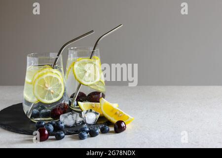 Kalte Getränke in kleinen Flaschen. Kirschen und Zitronenlimonade oder Cocktail. Stockfoto