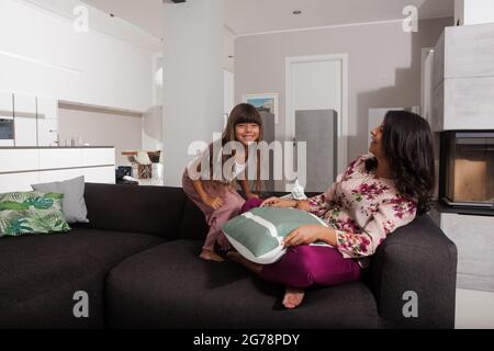 Mutter und Kind spielen auf dem Sofa im Wohnzimmer, harmonisch, Spaß haben Stockfoto