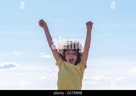 Kleiner lächelnder netter Junge mit langen Haaren hat Spaß beim Springen und Spielen. Spaß, Freizeit und Freizeit Konzept Kleiner lächelnder netter Junge mit langen Haaren hat Spaß beim Springen und Spielen. Spaß, Freizeit und Freizeit Konzept