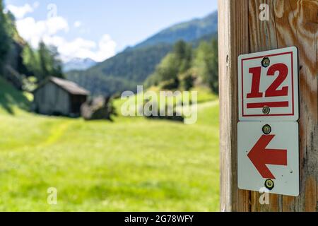 Europa, Österreich, Tirol, Ötztal Alpen, Ötztal, Zwieselstein, Wanderzeichen des Ötztaler Urweg vor einer grünen Wiese bei Zwieselstein Stockfoto