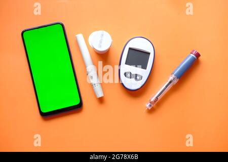Insulinstift, diabetische Messwerkzeuge ein Smartphone mit leerem Platz auf dem Tisch Stockfoto