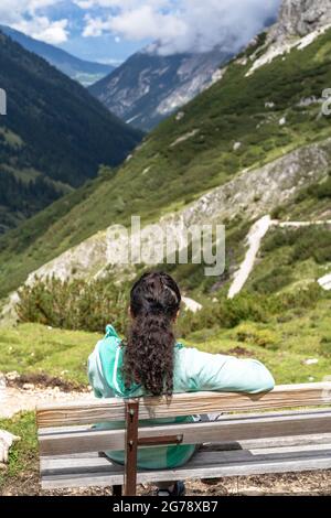 Europa, Österreich, Tirol, Stubaier Alpen, Pinnistal, Wanderer sitzt auf einer Bank und schaut hinunter in den Pinnistal Stockfoto