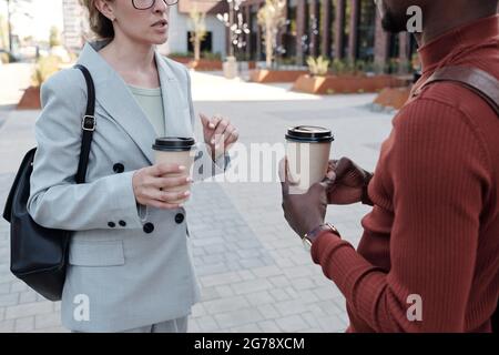 Elegante männliche und weibliche Mitarbeiter mit Getränken, die auf der Straße interagieren Stockfoto