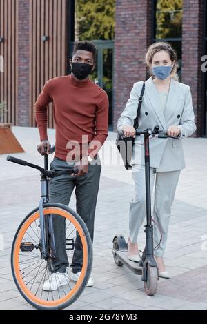 Afrikanischer Mann und kaukasische Frau mit Rollern, die Schutzmasken tragen Stockfoto