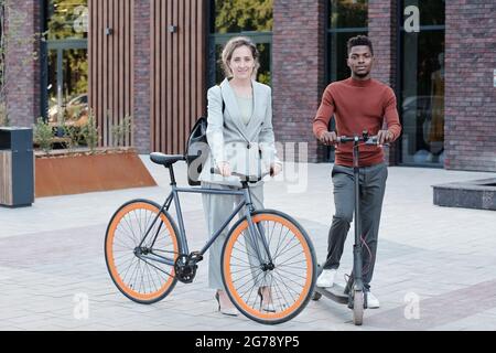 Moderne Geschäftsleute mit Fahrrad und Roller, die auf der Straße stehen Stockfoto