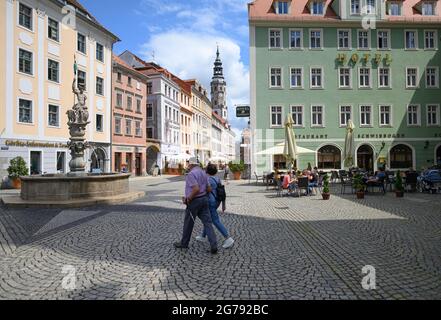 12. Juli 2021, Sachsen, Görlitz: Touristen wandern entlang der Brüderstraße, während Gäste die Outdoor-Gastronomie in einem Restaurant besuchen, im Hintergrund ist der Untermarkt mit dem Alten Rathaus zu sehen. Foto: Robert Michael/dpa-Zentralbild/dpa Stockfoto