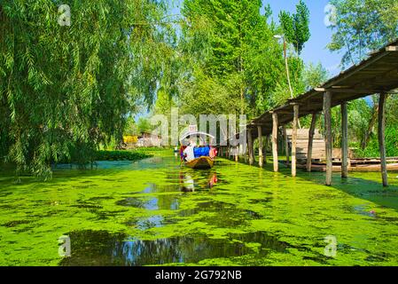 Menschen, die Shikara-Boote fahren und auf dem Fluss segeln. Eine Holzbrücke für Fußgänger. Blick auf den Dal Lake in Srinagar, Kashmir State, Indien. Juni 2018 Stockfoto