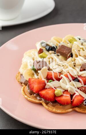 Herzwaffel mit Banane und Erdbeere mit Gummy Candy und Eis darauf. Stockfoto