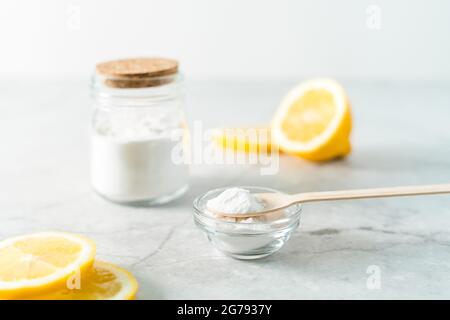 Umweltfreundliche natürliche Reinigungsmittel, Glas mit Backpulver, Zitrone und Holzlöffel auf Marmortisch Hintergrund. Bio-Zutaten für die hausgemachte Reinigung Stockfoto