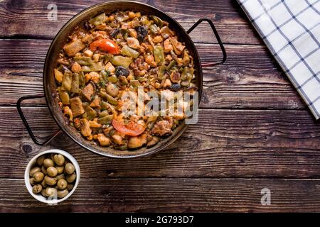 Holztisch mit Paella und grünen Oliven traditionelle hausgemachte Speisen. Paella mit Gemüse Stockfoto