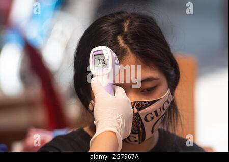 Jakarta, Indonesien. Juli 2021. Eine Frau lässt ihre Körpertemperatur während einer mobilen Impfkampagne in den dicht besiedelten Gebieten von Süd-Jakarta, Indonesien, am 12. Juli 2021 überprüfen. Quelle: Veri Sanovri/Xinhua/Alamy Live News Stockfoto