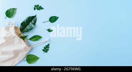 Kreatives minimalistisches Layout aus Blättern mit Öko-Baumwolltasche auf blauem Hintergrund. Flach liegend. Natur Nachhaltigkeit, Recycling-Konzept. Natürliche kosmetische Verwendung Stockfoto
