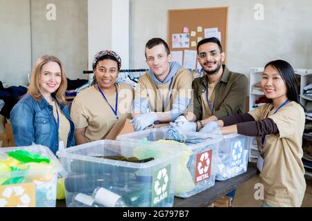 Team von multirassischen Freiwilligen, die mit Kunststoffbehältern am Tisch stehen Stockfoto