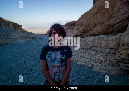 Ein kaukasischer Junge, 10-15 Jahre, der vor Felsen in Death Valley, Kalifornien, USA posiert Stockfoto