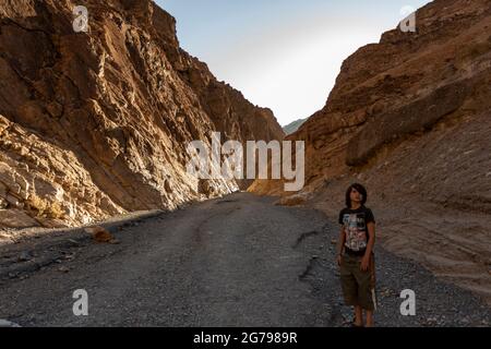 Ein kaukasischer Junge, 10-15 Jahre, der vor Felsen in Death Valley, Kalifornien, USA posiert Stockfoto