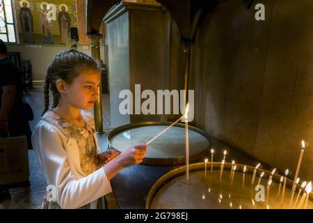 Ein Mädchen zündet eine Kerze in einer bulgarischen orthodoxen Kirche an, Sofia, Bulgarien, Stockfoto